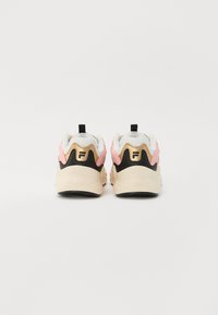 Des chaussures de sport rose et noire avec une semelle crème, dotées d'un design texturé, d'une languette et d'un logo sur le talon.