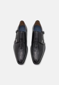 Black leather dress shoes with a pointed toe design, featuring brogue perforations and a side buckle detail. Smooth texture with a polished finish.