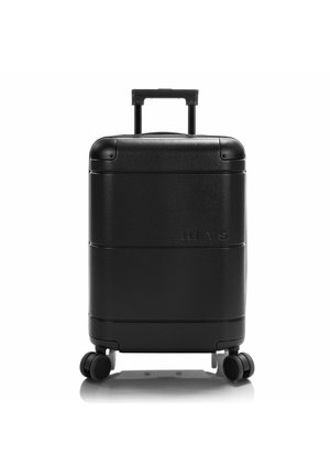 Maleta dura negra con textura suave, asas extensibles, cuatro ruedas y logo grabado. Forma rectangular compacta diseñada para viajar.