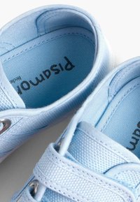 Scarpe in tela azzurro chiaro con superficie testurizzata, dotate di occhietti in argento, una fascia velcro e un interno imbottito per il comfort.
