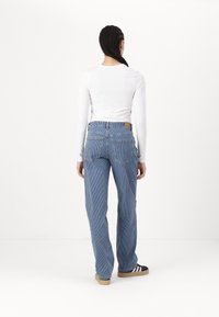 Blue striped denim pants with a straight-leg design, featuring a high waistband, back pockets, and a tan leather tag at the back.