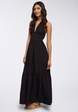 Abito lungo nero con scollo a halter e corpino arricciato, caratterizzato da una gonna a strati. Il tessuto morbido e la silhouette fluida creano una vestibilità rilassata.