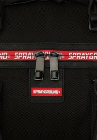 Mochila negra con acabado texturizado, que presenta la marca en rojo "SPRAYGROUND", dos cremalleras negras y un diseño robusto.