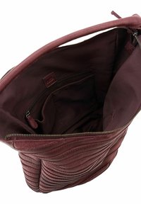 Sac à main en cuir bordeaux avec texture matelassée, fermeture zippée et poches intérieures. Doublure en tissu doux complète le design structuré.
