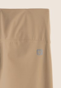 Tessuto beige con una superficie liscia, caratterizzato da un logo sottile nell'angolo in basso e una cucitura lungo il bordo superiore.