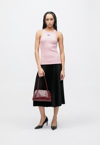 Pink sleeveless tank top, black pleated midi skirt, black high heels, and a burgundy textured handbag with a curved shape.