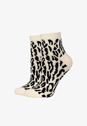 Een paar enkellange sokken met een zwart-wit luipaardprintpatroon op een crèmekleurige achtergrond.