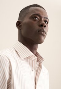 Camicia con colletto a righe verticali rosa chiaro e bianche. Realizzata in cotone, presenta un davanti con bottoni e un tessuto testurizzato.