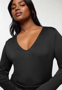 Czarny body długi rękaw z głębokim dekoltem w kształcie V, wykonane z gładkiego materiału, charakteryzujące się gładką teksturą i dopasowanym krojem.