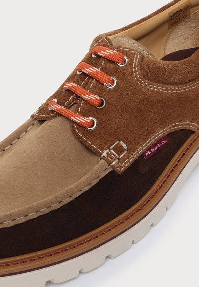 Chaussure décontractée en daim marron avec lacets orange, détails blancs cousus, semelle superposée et petite étiquette rouge PS Paul Smith sur le côté.