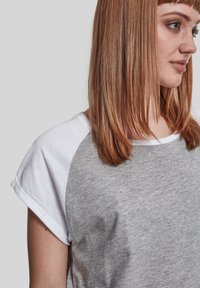 Grå og hvid kortærmet T-shirt med rund halsudskæring og rullede ærmer, lavet af blød bomuldsblanding. Struktureret overflade synlig.