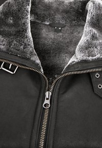 Schwarze Lederjacke mit einem grauen Kunstfellkragen, Reißverschluss vorne und metallischen Akzenten. Strukturiertes Finish mit sichtbaren Nähdetails.