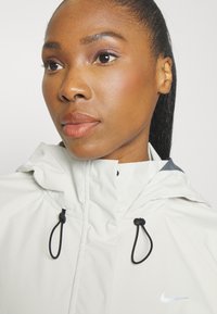 Nike Performance STORM-FIT SWIFT - Running jacket - pale ivory/black/silver
