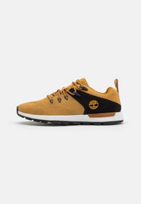Žlutý textilní a černý semišový sneaker s kulatou špičkou, šněrováním, výrazným logem na boku a texturovanou gumovou podrážkou.
