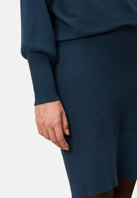 Zestaw sweterków z dzianiny, prążkowany, w głębokim granatowym kolorze, z długimi rękawami, luźnym krojem oraz teksturowanym wykończeniem na swetrze i spódnicy.