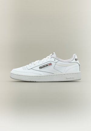 Balti žemi Reebok sportbačiai su raišteliais priekiniame krašte, perforuota nosimi, tekstūruota pada ir Reebok logotipu su Didžiosios Britanijos vėliava šone ir kulne.