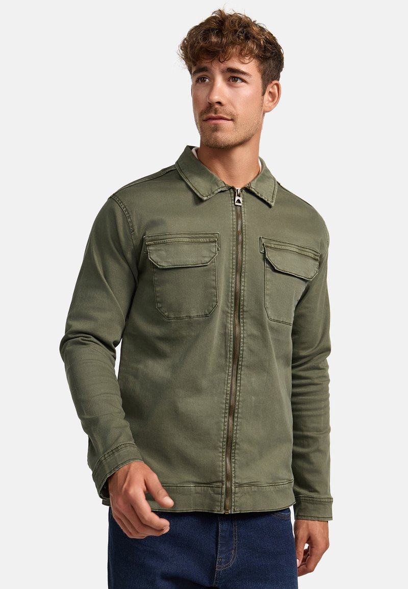 Olivgrüne Zip-Jacke mit Kragen, zwei Brusttaschen, langen Ärmeln und glatter Textur. Mit einem Metallreißverschluss und gestickten Details.