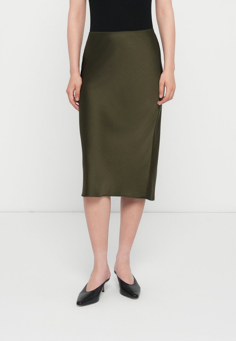 Olive green satin midi skirt with a smooth texture, tailored shape, and hemline finishing just below the knee. Paired with black mules.