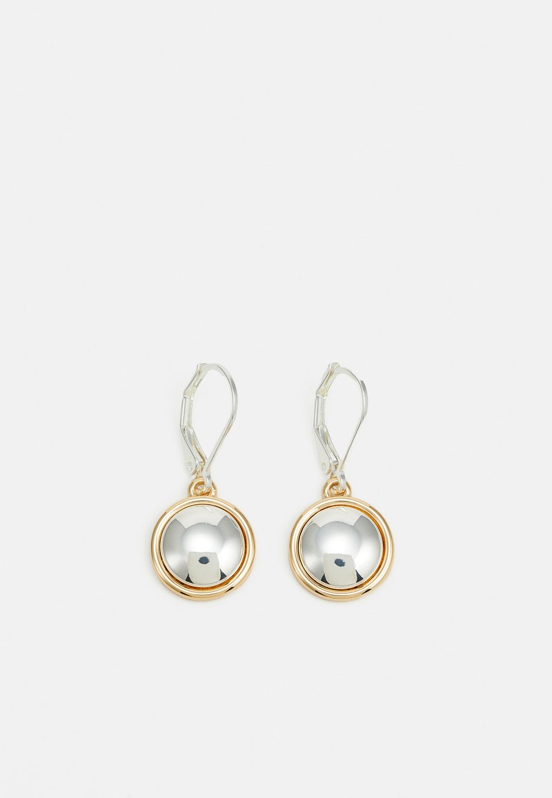 Des boucles d'oreilles en ton or et argent présentent des disques centraux ronds et réfléchissants entourés d'un anneau doré, avec un fermoir à crochet pour un port sécurisé.