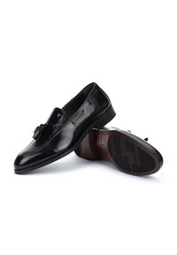 Mocasines de cuero negro con un acabado suave, que presentan un borlas decorativas y una suela texturizada para un mejor agarre.