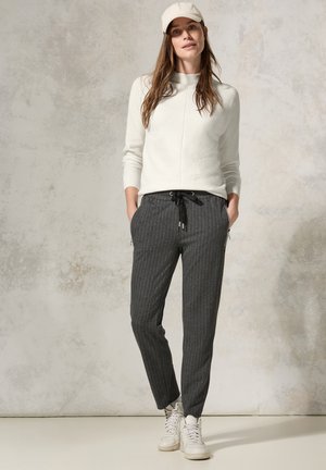 Lichtgrijze geribbelde trui, taps toelopende grijze pinstriped broek met trekkoord, en witte high-top sneakers. Eenvoudig ontwerp met functionele zakken.