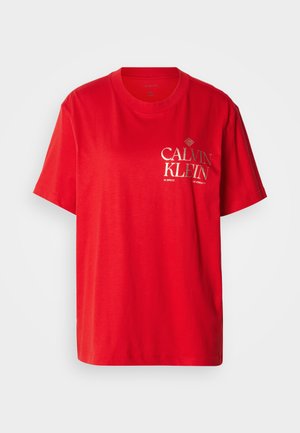 Piros pamut póló kerek nyakkivágással, rövid ujjakkal, elől "CALVIN KLEIN" felirat fehér és arany betűkkel.