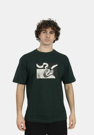 T-shirt di cotone verde scuro con stampa grafica centrata in bianco e nero con vortici astratti. Maniche corte e vestibilità rilassata.