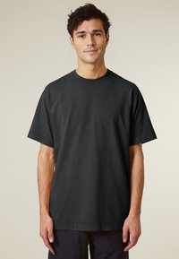 Black cotton t-shirt with a round neck and short sleeves. Features a relaxed fit and subtle texture. Simple, uniform design without embellishments.