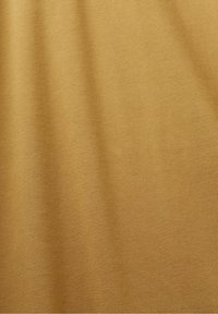 Tissu beige texturé avec des plis subtils, montrant un motif tissé serré et une surface lisse.