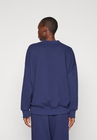 Mørkeblå sweatshirt med afslappet pasform, ribbede manchetter og kant. Har en rund hals og blød tekstur, designet til komfort og bevægelsesfrihed.