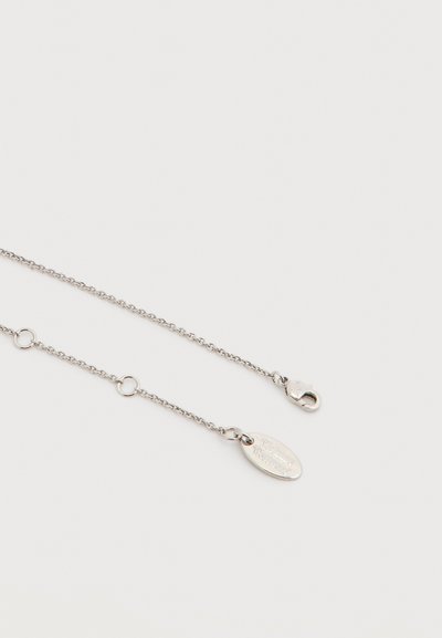 Ασημένιο κολιέ με αλυσίδα, κούμπωμα καραβιδάκι και οβάλ πλακέτα με χαραγμένο το όνομα του brand σε λευκό φόντο.