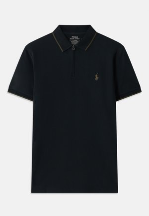 Svart pikétröja med halvdragkedja, kontrasterande krage och en liten broderad logotyp på vänster sida. Tillverkad av ett glattt tyg.