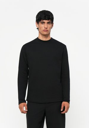 Svart langermet T-skjorte laget av myk kvalitet, med rund hals og vanlig passform. Minimalistisk design uten synlige mønstre eller detaljer.