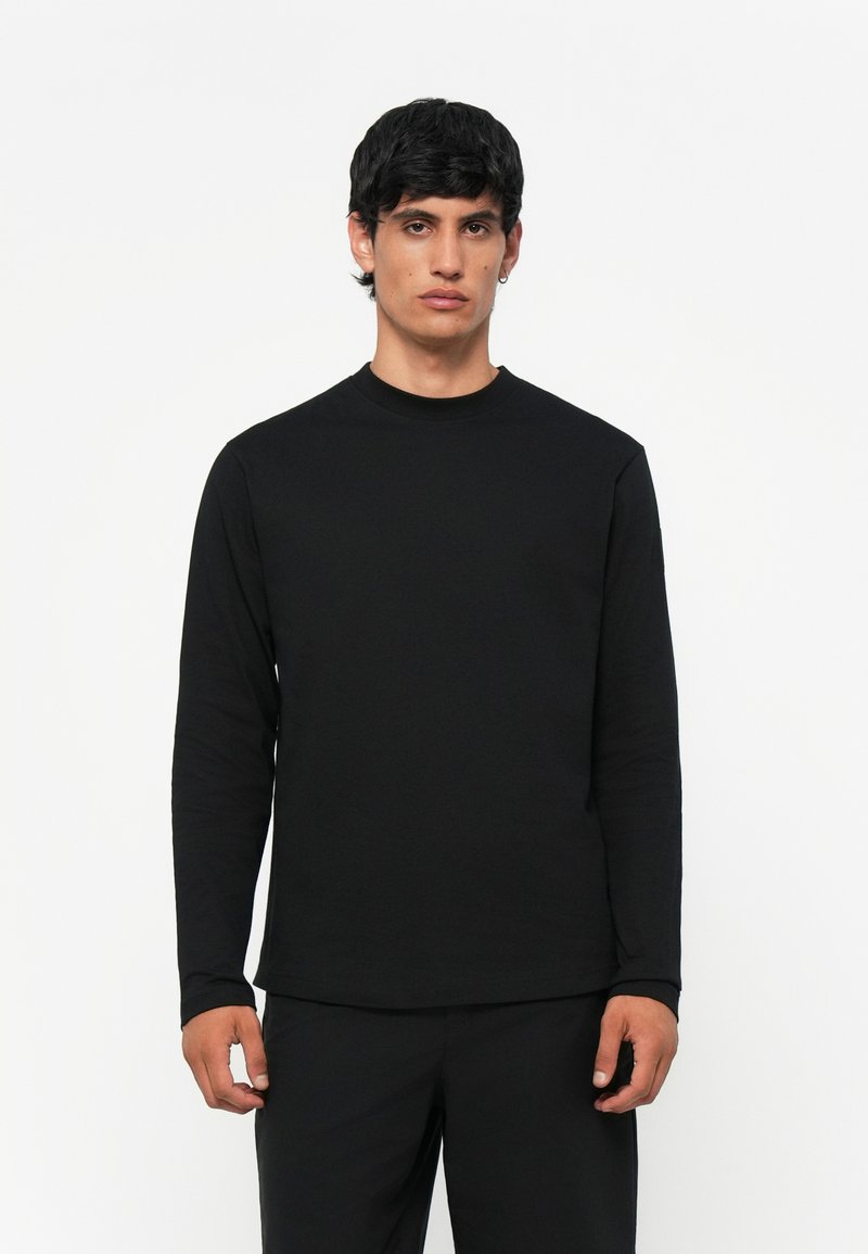 Svart langermet T-skjorte laget av myk kvalitet, med rund hals og vanlig passform. Minimalistisk design uten synlige mønstre eller detaljer.