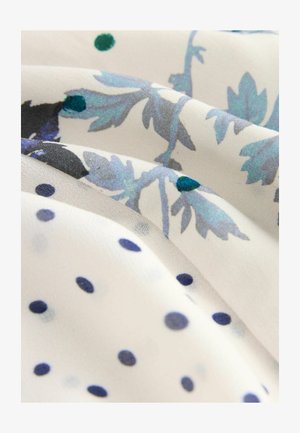 Šviesi, permatoma medžiaga su abstrakčiu gėlių raštu mėlyna ir žalia spalvomis, su tamsiai mėlynomis taškeliais ant baltos foninės.