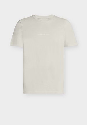 Ανοιχτό μπεζ κοντομάνικη μπλούζα με στρογγυλή λαιμόκοψη και διακριτικό λευκό κείμενο "Denim Design Studio" στο κέντρο του στήθους.