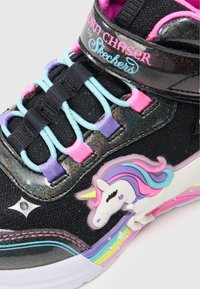 Czarne sneakersy z wielokolorowymi sznurowadłami, z motywem jednorożca po boku oraz iryzującymi akcentami na górze i podeszwie.