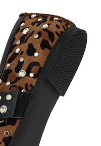 Leren laarzen met luipaardprint en zwarte accenten, voorzien van zilveren studs en een gestructureerde rubberen zool. Zijaanzicht dat unieke ontwerpelementen laat zien.