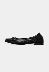 Chaussure plate en cuir verni noir à bout arrondi, petit talon et détail de boucle décorative à l'avant, vue de profil sur fond blanc.