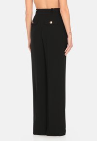 Pantaloni neri su misura con vita alta, gambe larghe e tasche posteriori decorative con dettagli in bottone dorato. Tessuto dalla consistenza liscia.