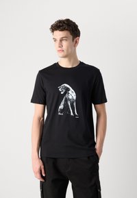 Black cotton t-shirt featuring a large white graphic of a dog. Short sleeves and a crew neckline. Simple, modern design with no additional patterns.
