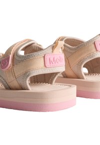 Ανοιχτό μπεζ σανδάλια με ροζ λεπτομέρειες, που διαθέτουν υφασμάτινη ανθεκτική σόλα και ρυθμιζόμενες λουρίδες για ασφαλή εφαρμογή. Ορατή ετικέτα της μάρκας.