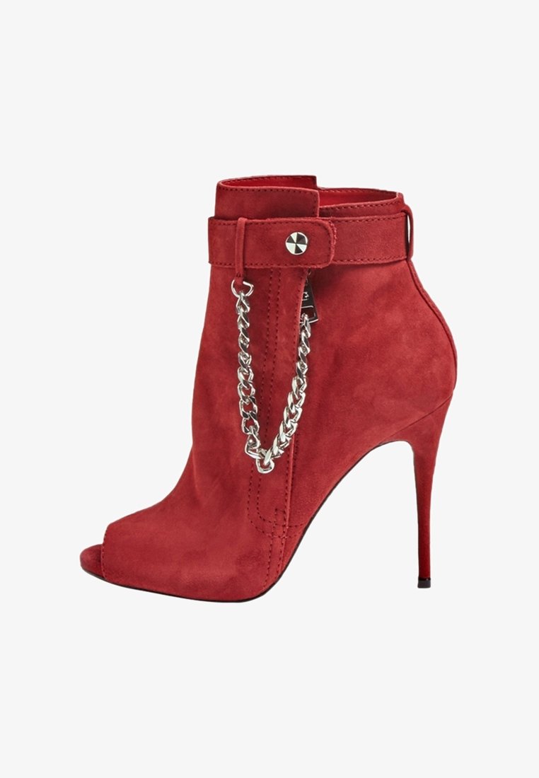 Bottine à talons hauts en daim rouge avec ouverture à l'avant, chaîne argentée décorative et bride avec fermeture à clous autour de la cheville.