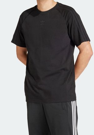 T-shirt noir à manches courtes en coton, doté d'un col rond, de manches raglan et d'un logo Adidas discret sur la poitrine.