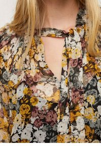 Kirkas kukallinen paidat keltaisena, valkoisena, harmaana ja burgundina, jossa on röyhelöyksityiskohtia ja sidottu kaula-aukko.