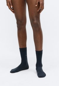 Dunkelblaue Baumwollsocken mit geripptem Muster, knielang und einem kleinen Logo am Knöchel. Weiches, elastisches Material für hohen Tragekomfort.