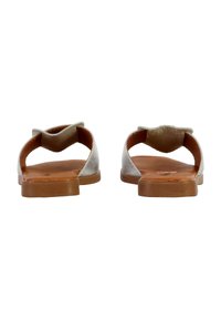Sandali piatti beige con un retro arrotondato, un design a strappo asimmetrico e una parte superiore liscia e texturizzata.