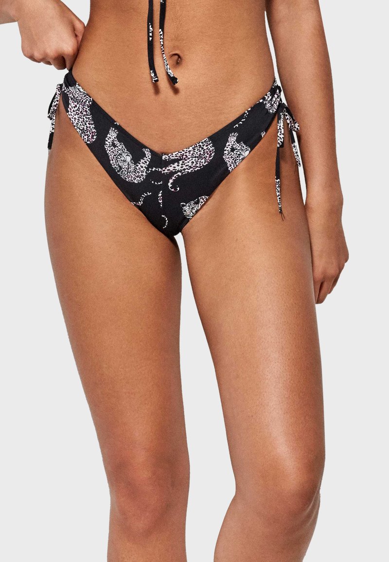 Parte inferior de bikini negra con un patrón de estampado de leopardo, que cuenta con cierres laterales ajustables y una textura de tejido suave. Diseño de corte bajo.