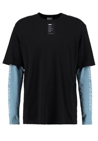 Schwarzes T-Shirt mit kurzen Ärmeln und attachierten blauen langen Ärmeln. Die blauen Ärmel haben den weißen Schriftzug "PUMA". Hergestellt aus weichem Stoff.