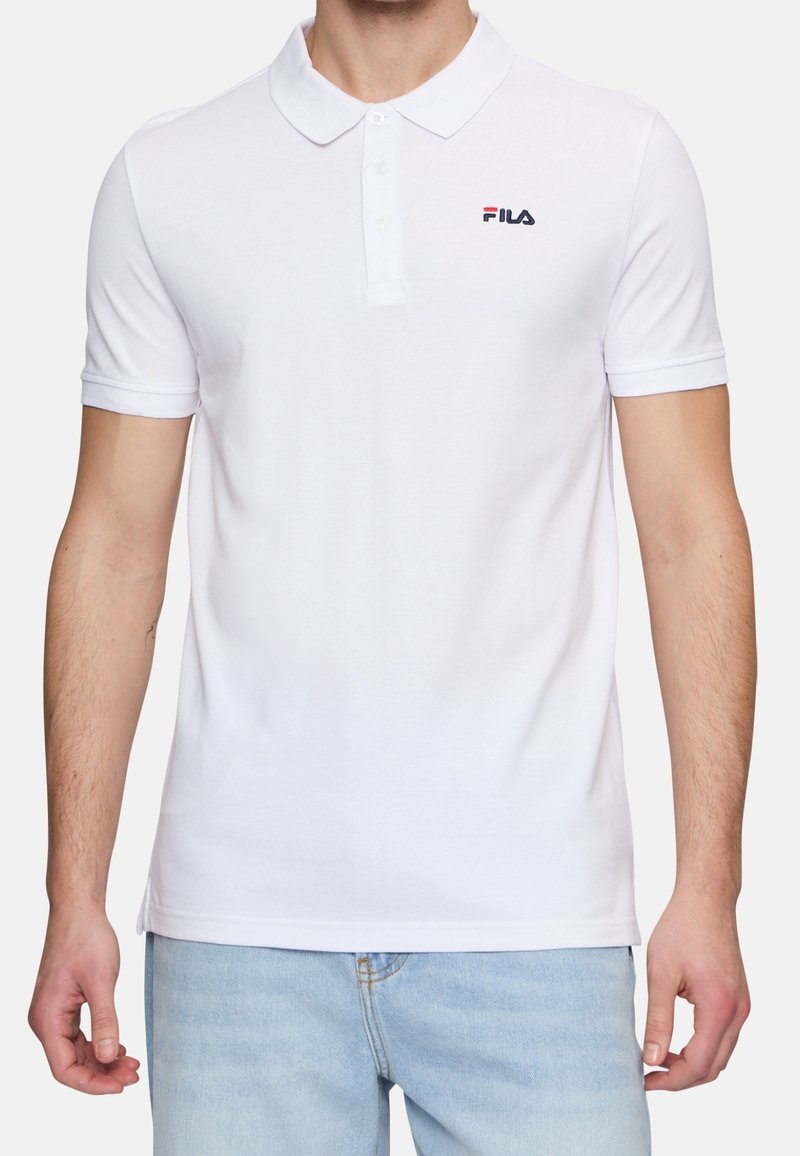 Polo blanc en coton avec un col rabattable. Présente un petit logo Fila bleu et rouge sur la poitrine gauche. Manches courtes.